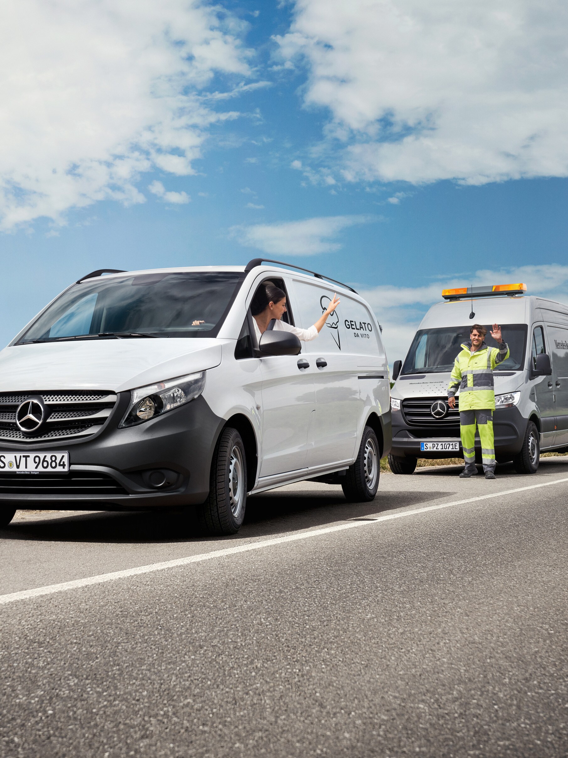A person in a white Mercedes-Benz Vito van waving to a service technician parked by the side of the road.