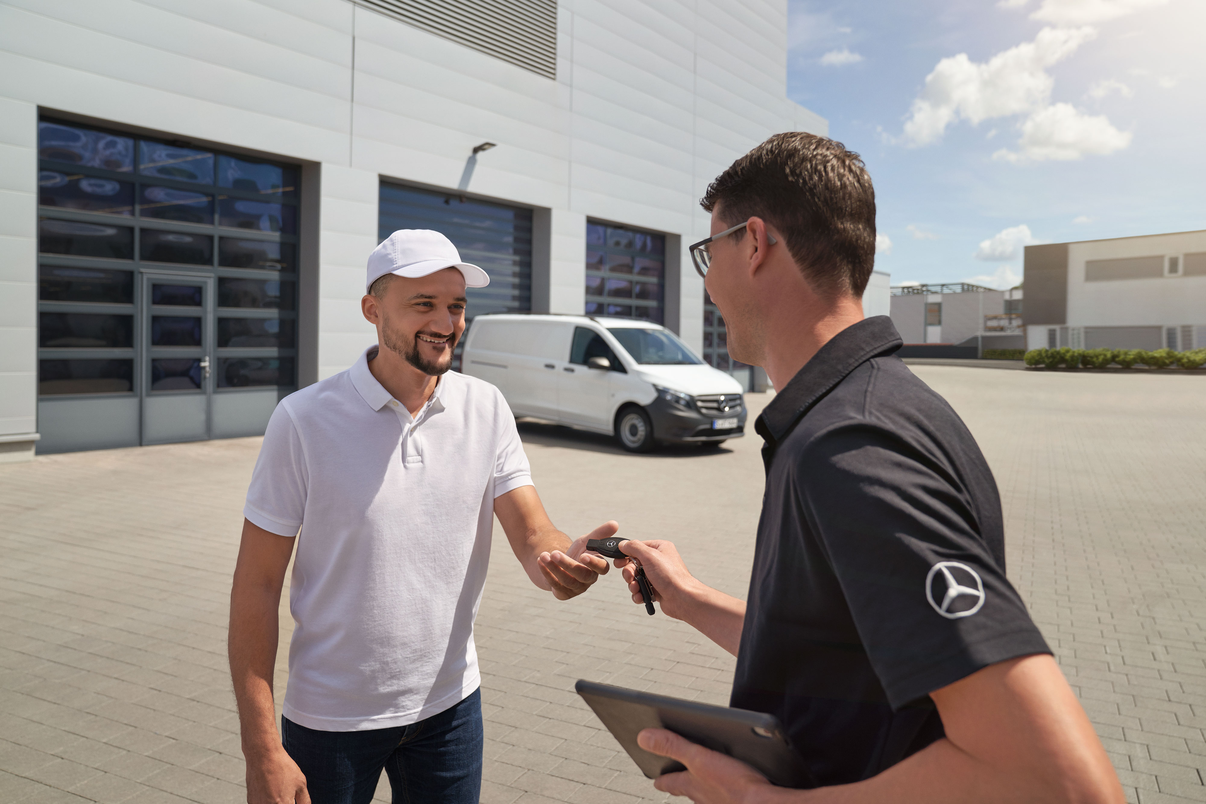 Mercedes-Benz | Convenience | Pick-up and delivery service Mercedes-Benz technican handing over keys to a customer with a white Mercedes-Benz Vito van in the background.