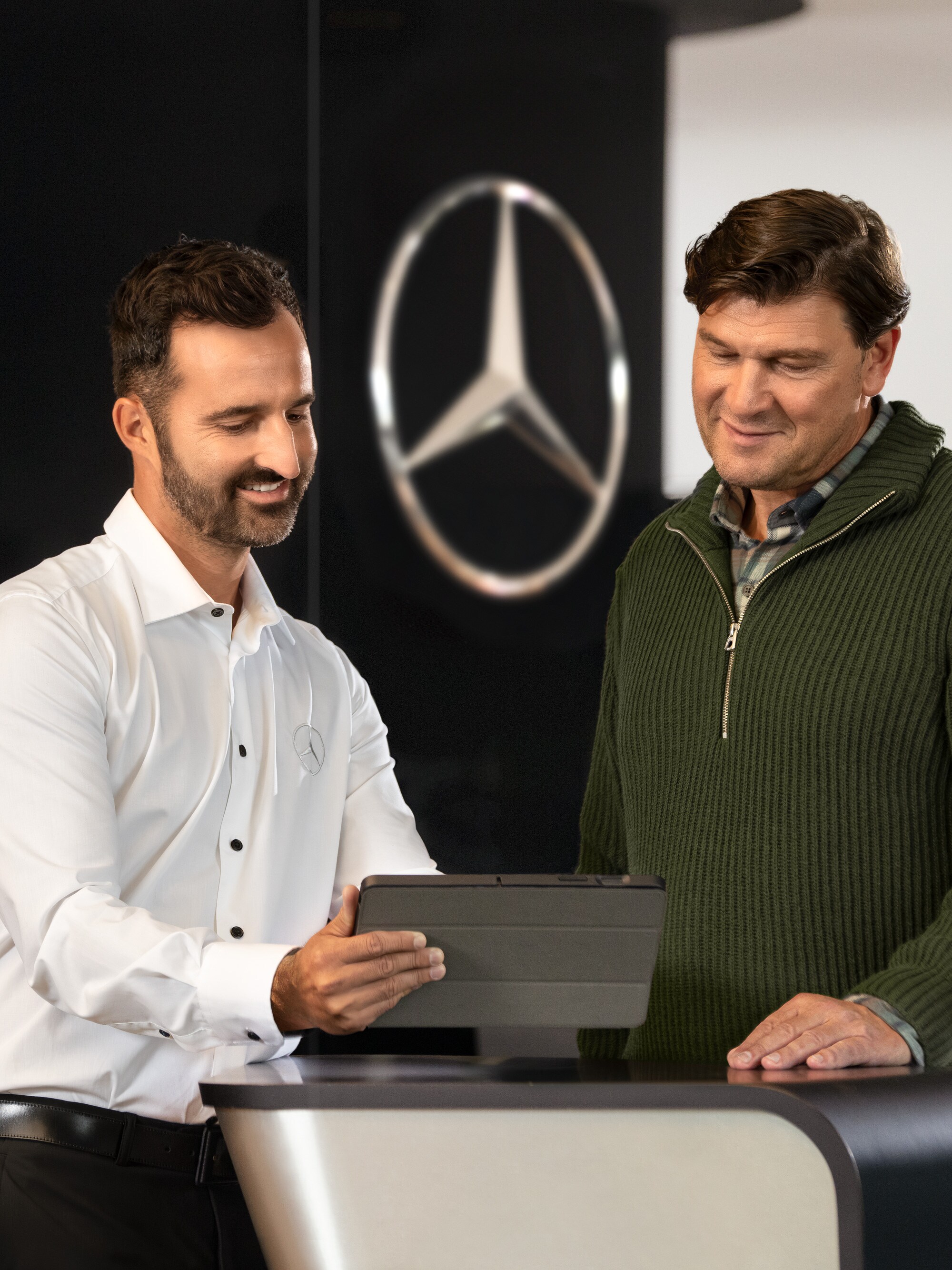 Mercedes-Benz employee talking to customer while looking at a table device.
