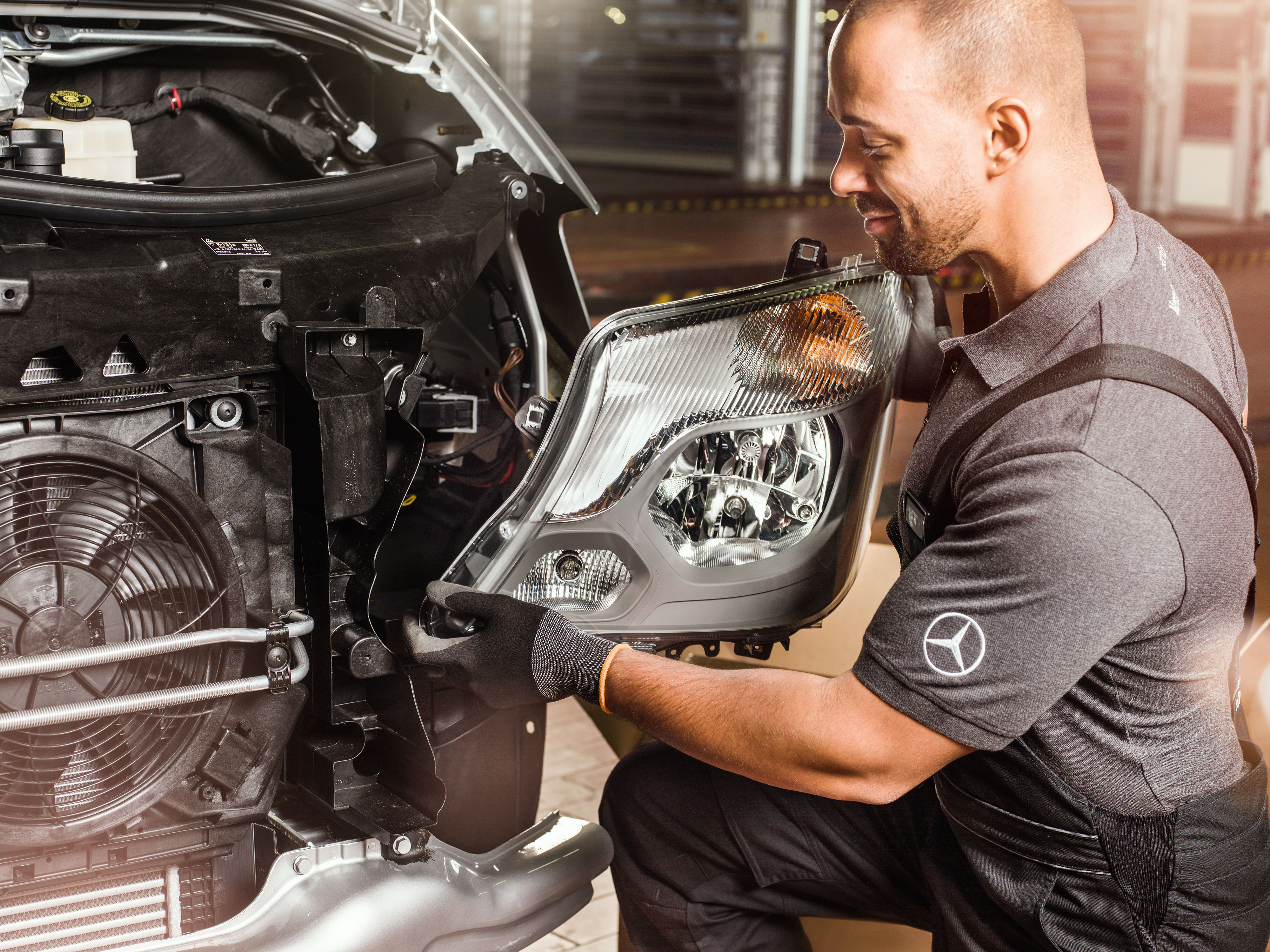 Mercedes-Benz | Vans Quality GenuineParts Mechanic checking Mercedes-Benz Genuine Parts in front of an open Sprinter engine, matching the Mercedes spare parts catalogue.