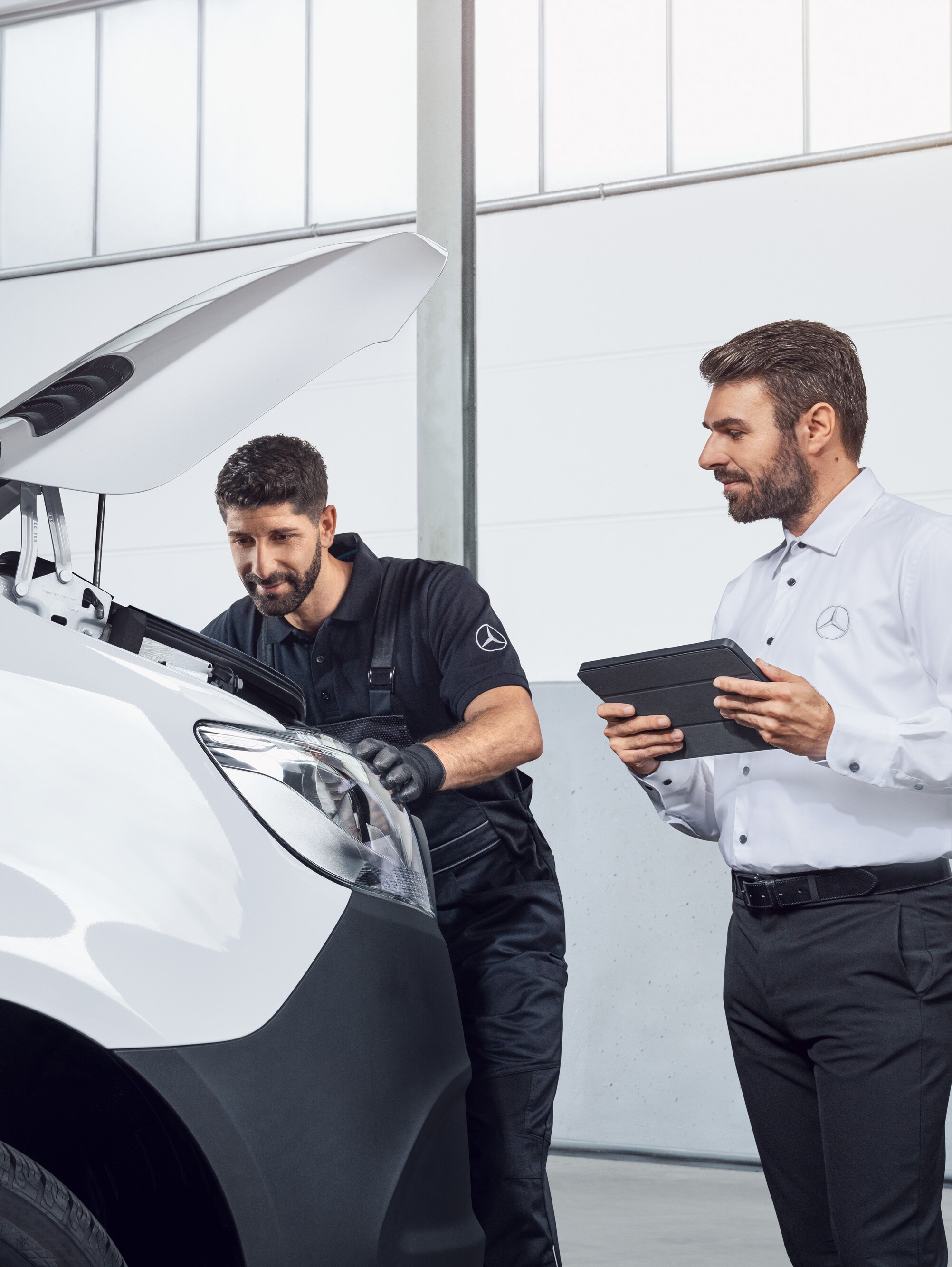 Two men testing a Mercedes Sprinter with tablet and open bonnet, topic: Mercedes-Benz Sprinter spare parts.