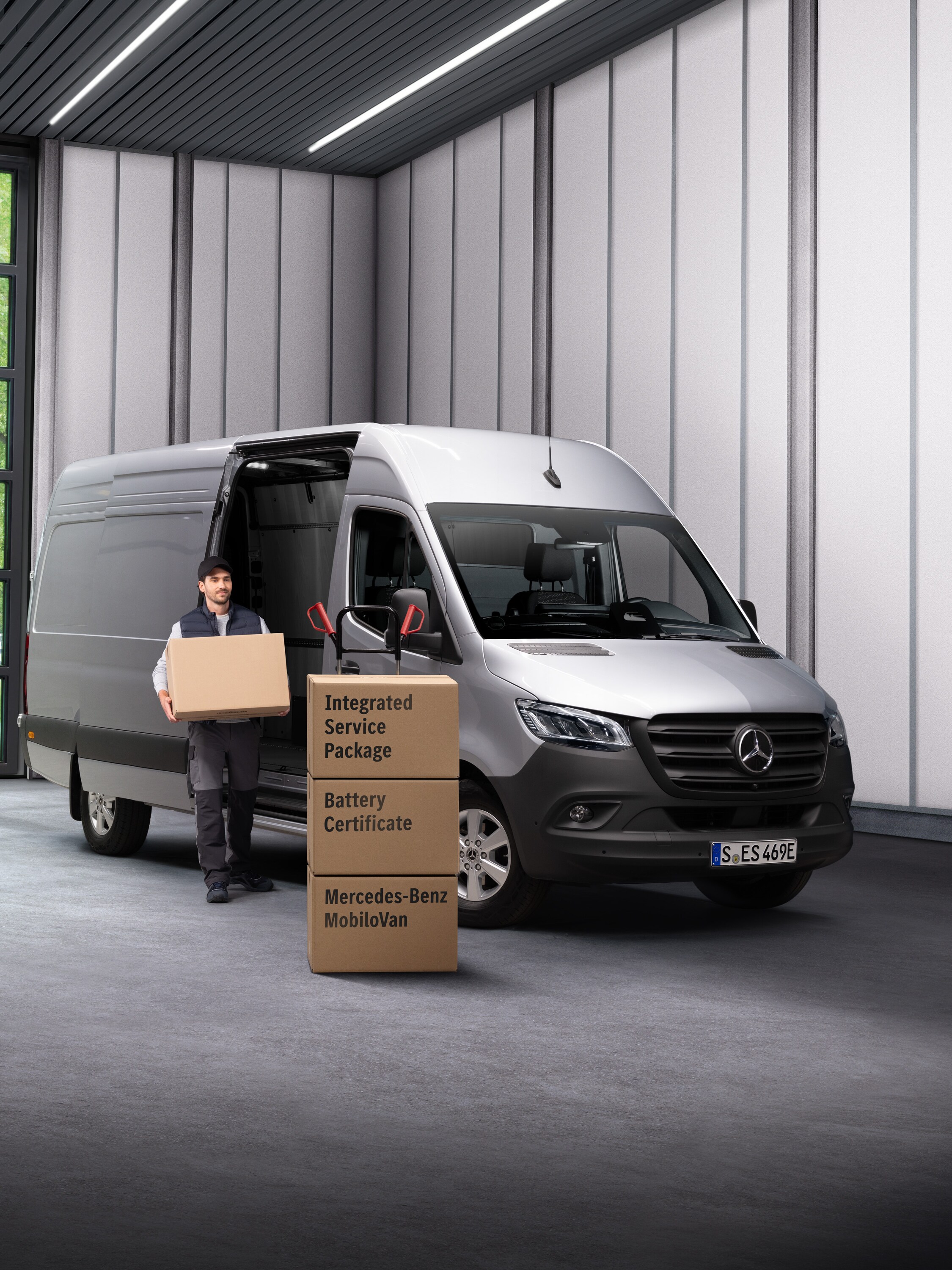 A Mercedes-Benz electrical service employee carrying boxes out of a transport