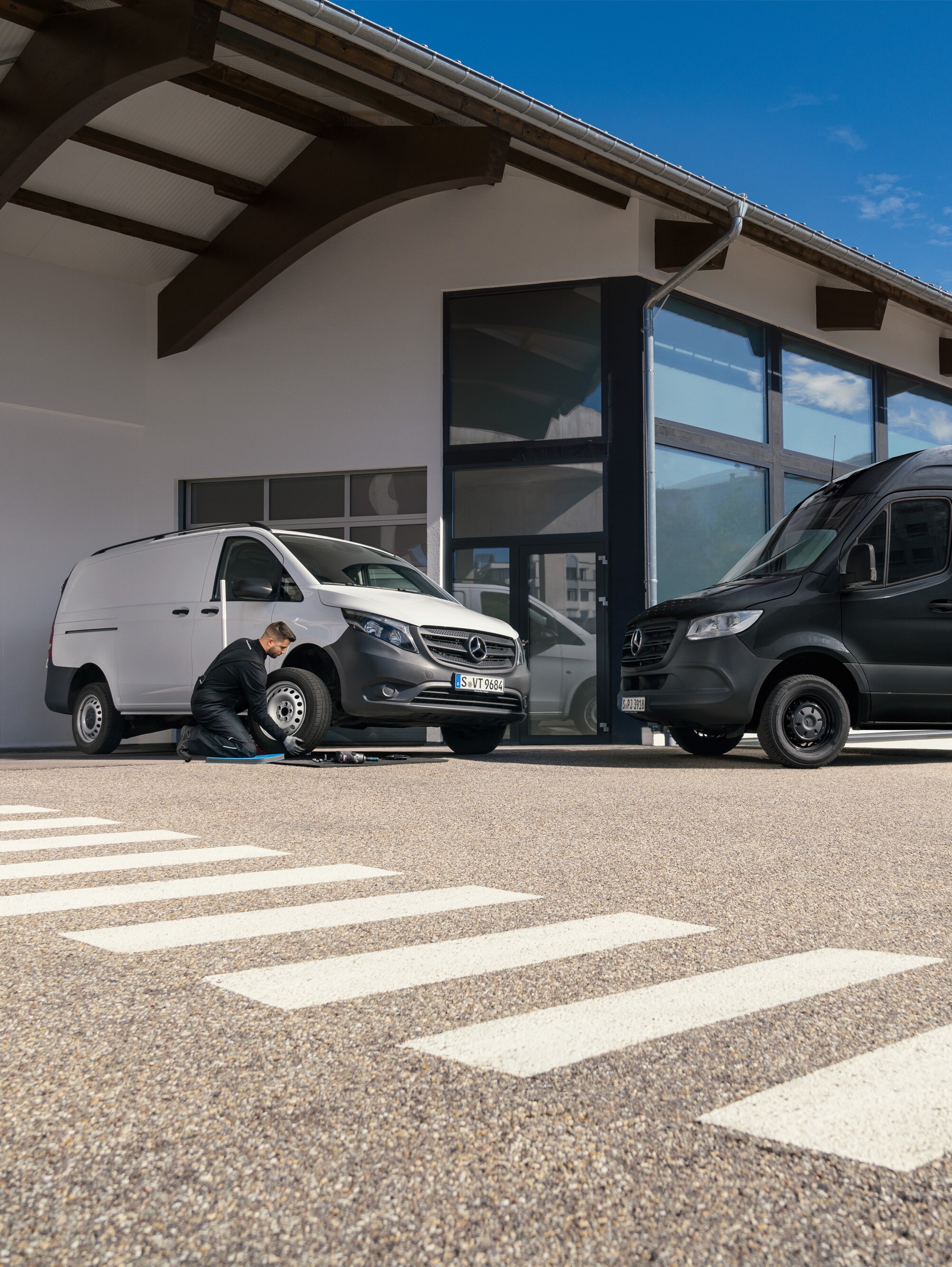 A technician changes a tyre on a white Mercedes-Benz Vito van infront of a showroom.