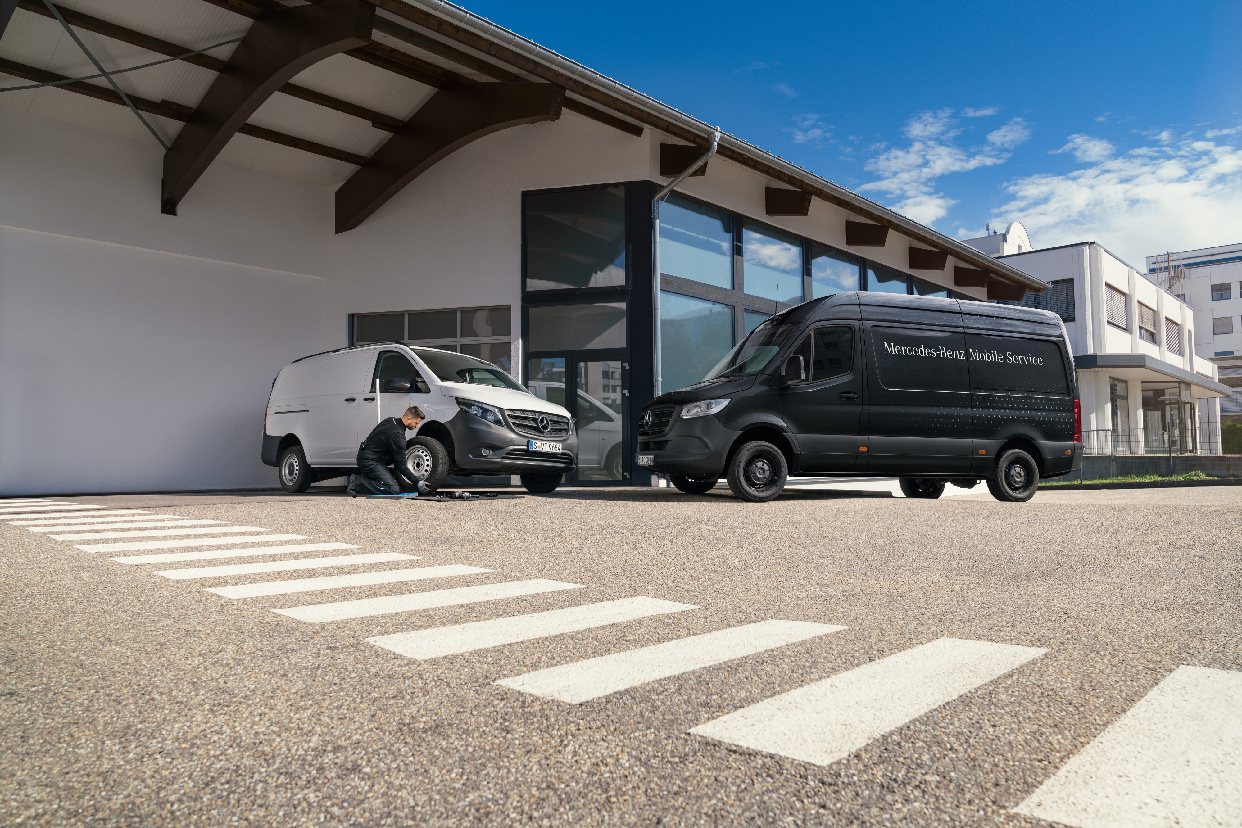 Mercedes-Benz | Mobile Service | Braking system A technician changes a tyre on a white Mercedes-Benz Vito van infront of a showroom.