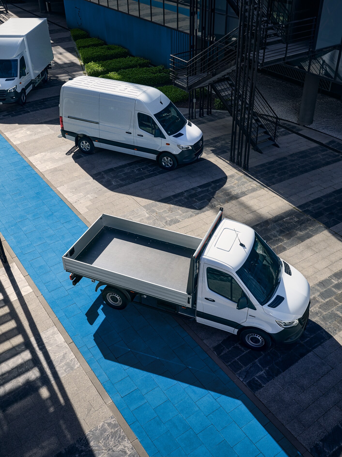 White Mercedes-Benz eSprinter Panel, Chassis Platform and Luton Box Vans all parked outside an office building. 