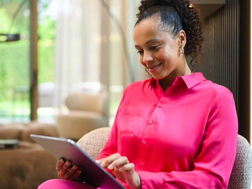 A person at home looking at a tablet device and smiling