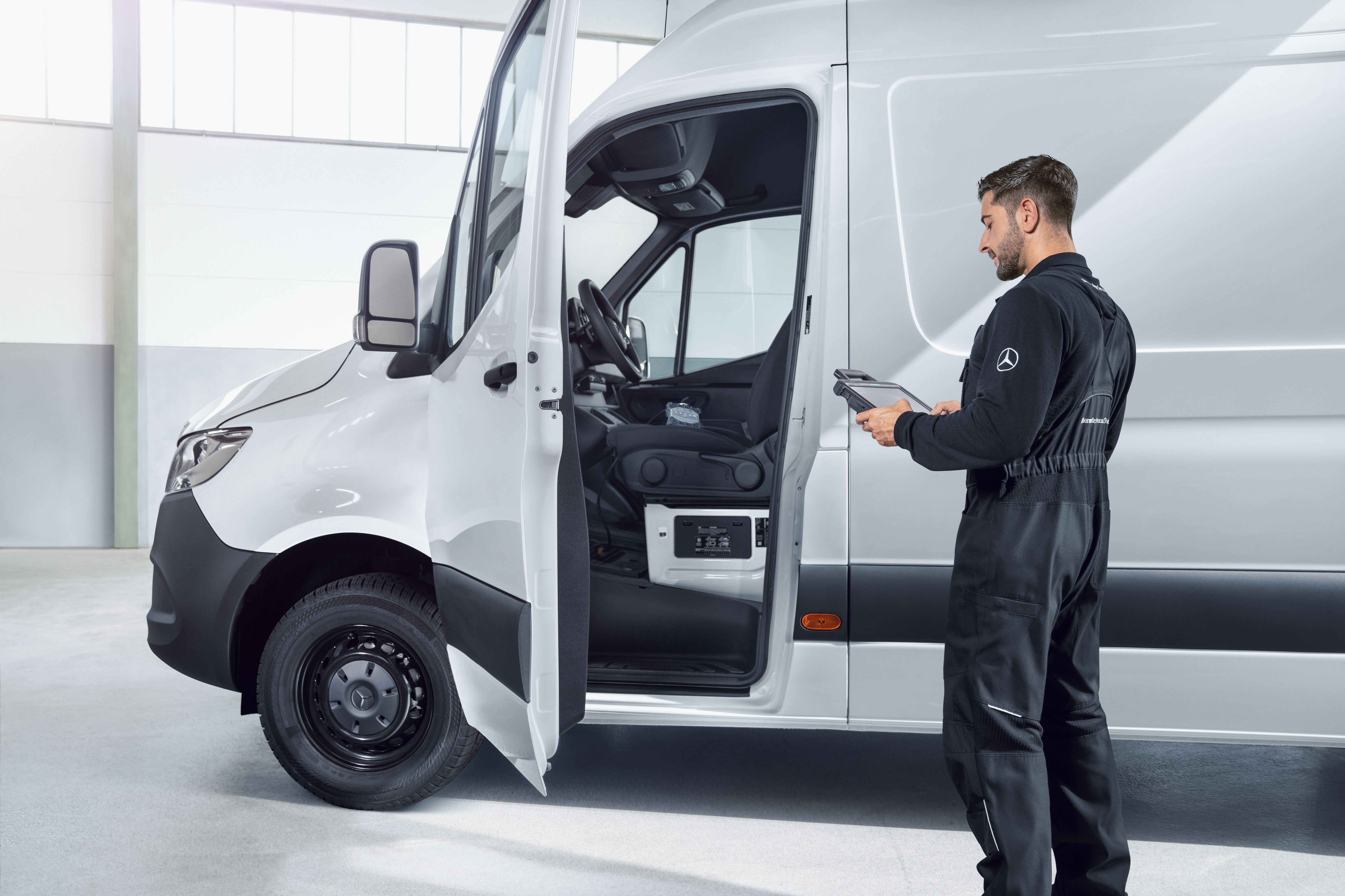 ISP Technician in uniform inspecting a white Mercedes-Benz eSprinter van.