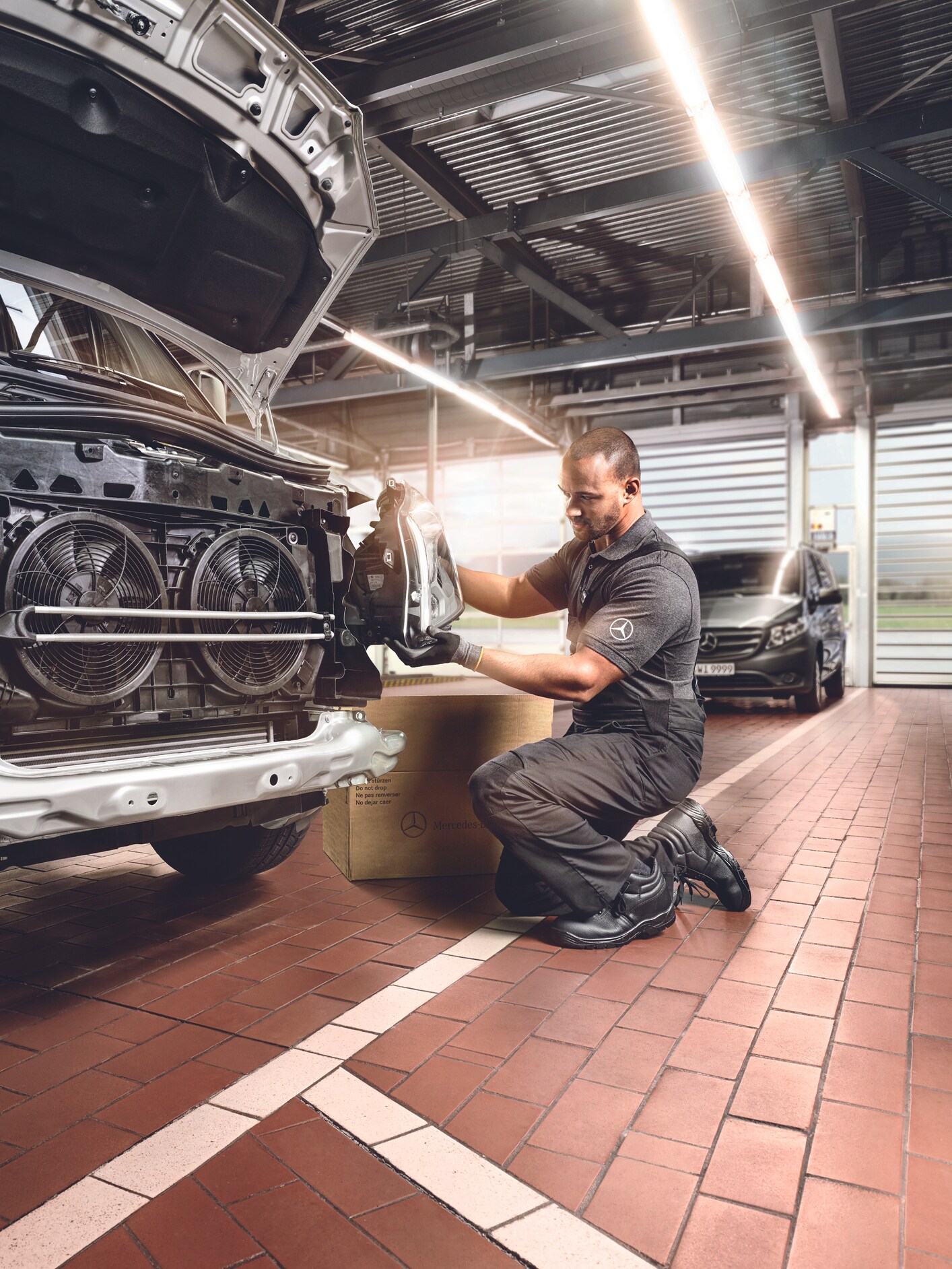A technician installing a part onto the exposed front end of a van.
