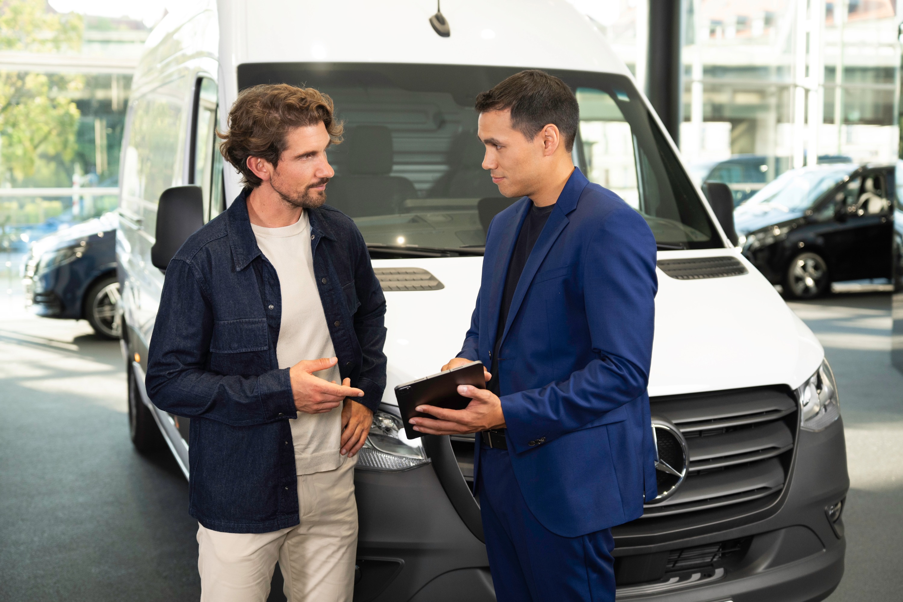 Financing your van | Mercedes-Benz Vans Two men looking at a tablet device in front of a Mercedes-Benz Sprinter Panel Van.