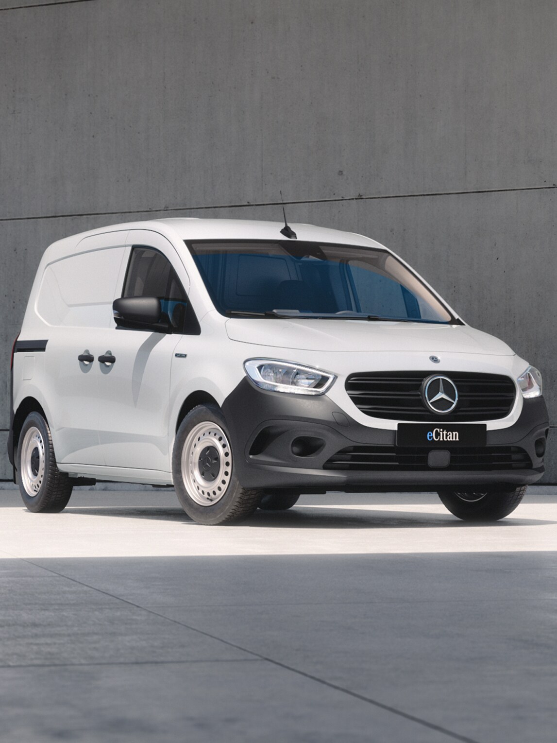 White Mercedes-Benz eCitan Panel Van parked by modern concrete structure.