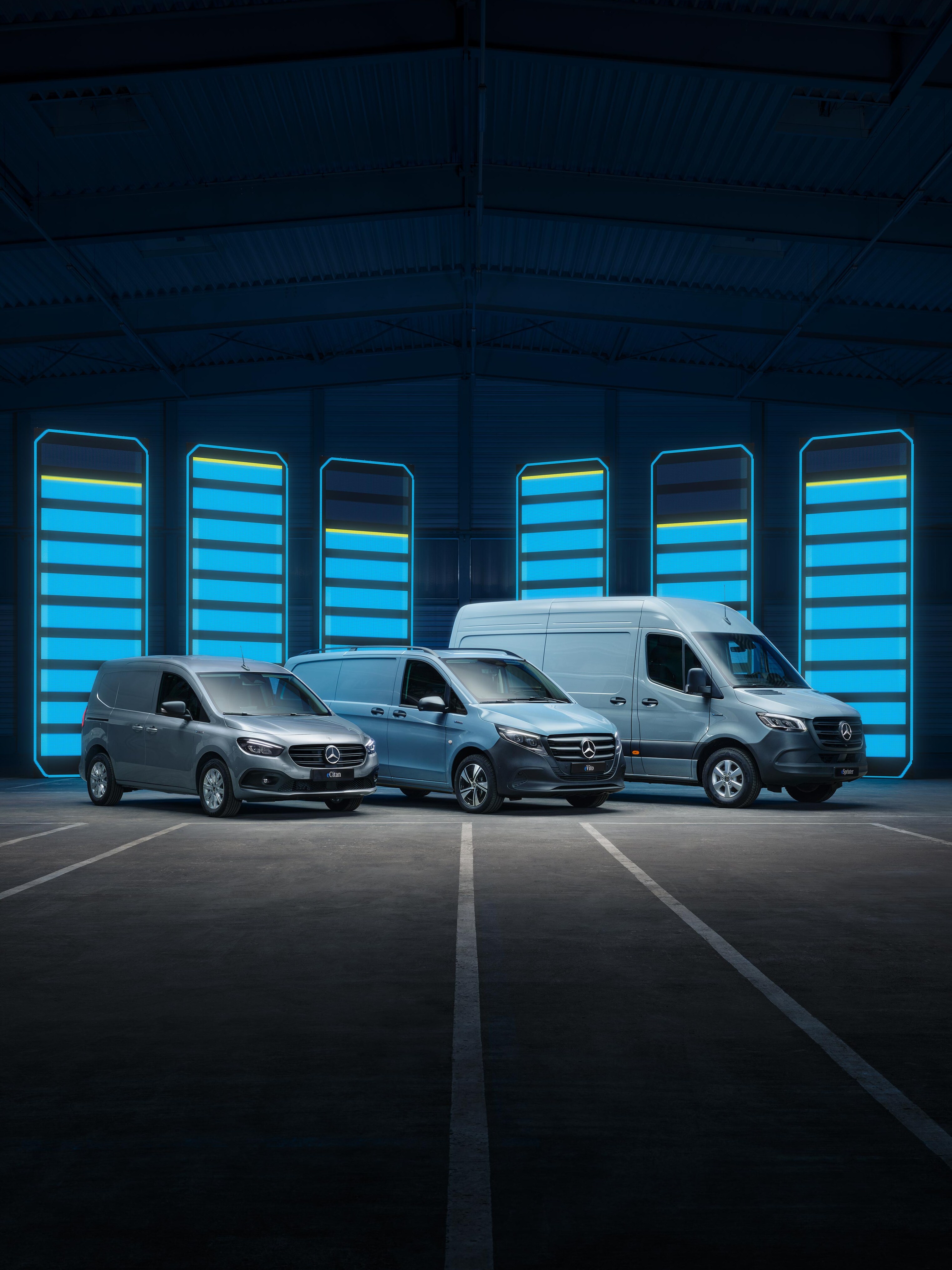 Mercedes-Benz eCitan, eVito and eSprinter  electric panel vans parked in a row in front of a bue battery charging graphic. 